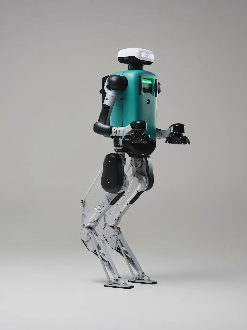Bipedal robot with teal torso, white and black limbs, and digital face on a white background.